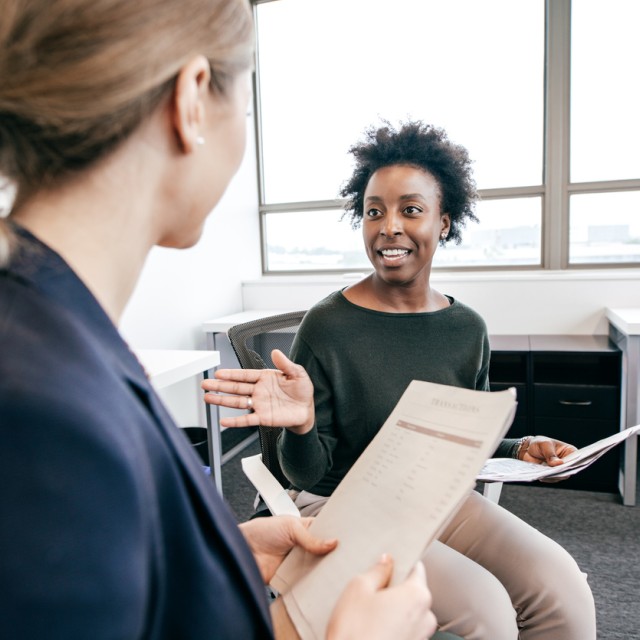 Women in conversation holding paperwork
